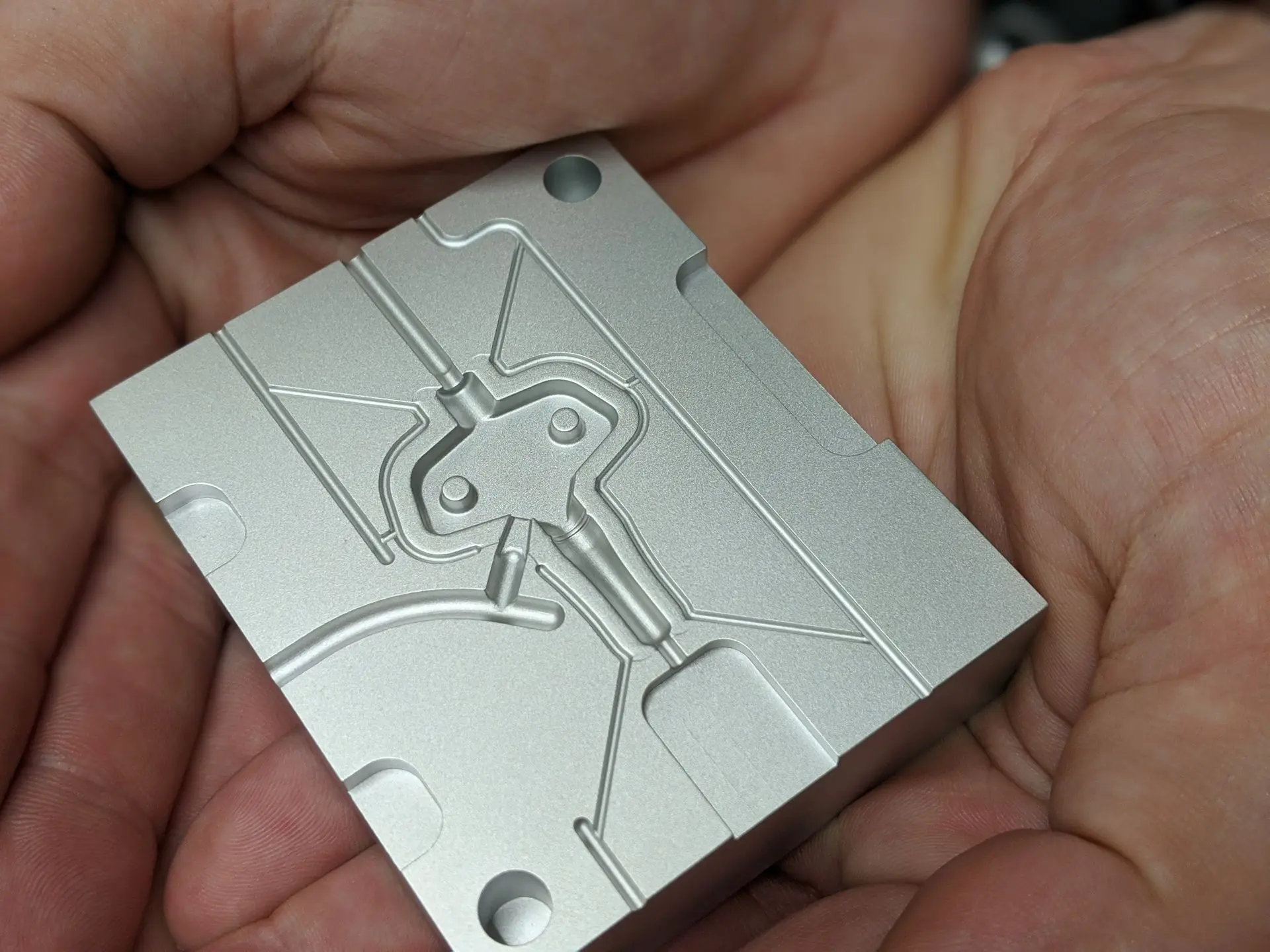 Hands holding a precision CNC-milled aluminum plate